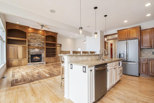 kitchen featuring appliances with stainless steel finishes, light wood-type flooring, a sink, and a kitchen breakfast bar