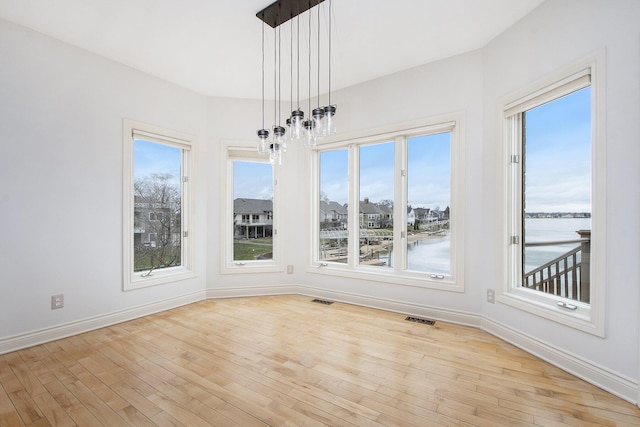 unfurnished dining area with visible vents, light wood-style flooring, and baseboards