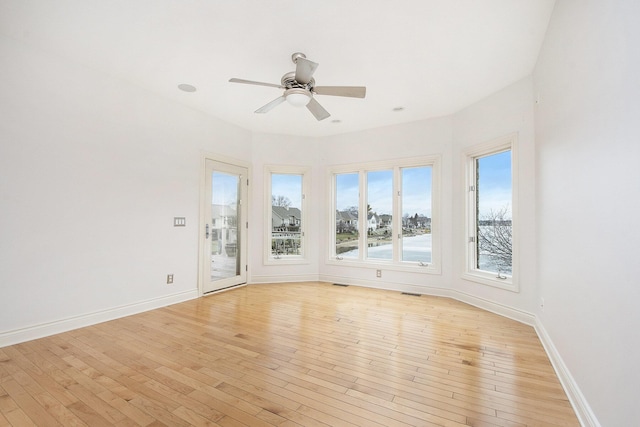 spare room featuring a ceiling fan, baseboards, visible vents, and light wood finished floors