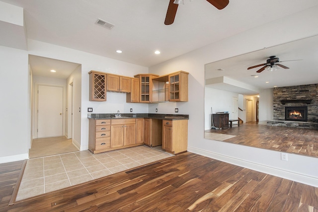 kitchen featuring visible vents, dark countertops, light wood-style flooring, glass insert cabinets, and a sink