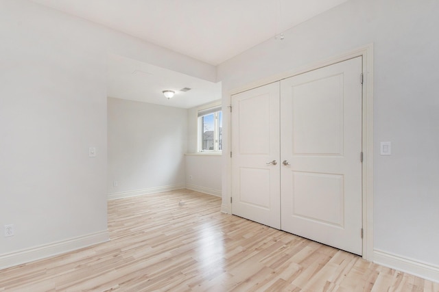 unfurnished bedroom with light wood-style floors, baseboards, and a closet