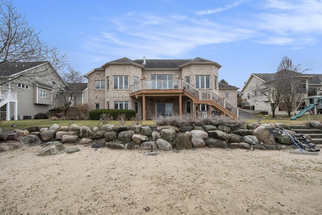 rear view of property featuring brick siding, stairway, and a playground