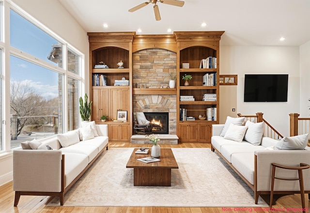 living room with light wood-style floors, recessed lighting, a fireplace, and built in shelves