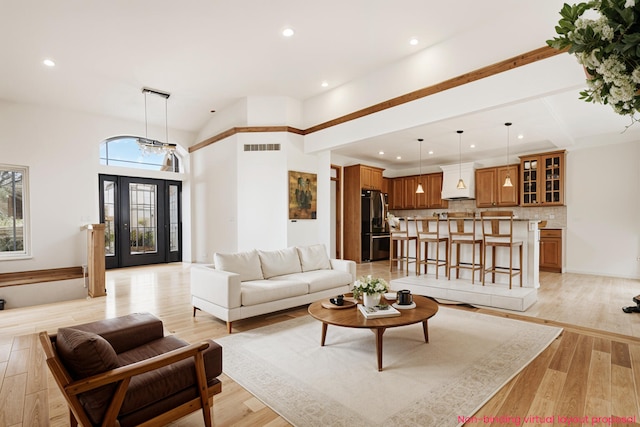 living room featuring light wood-style floors, a high ceiling, visible vents, and recessed lighting