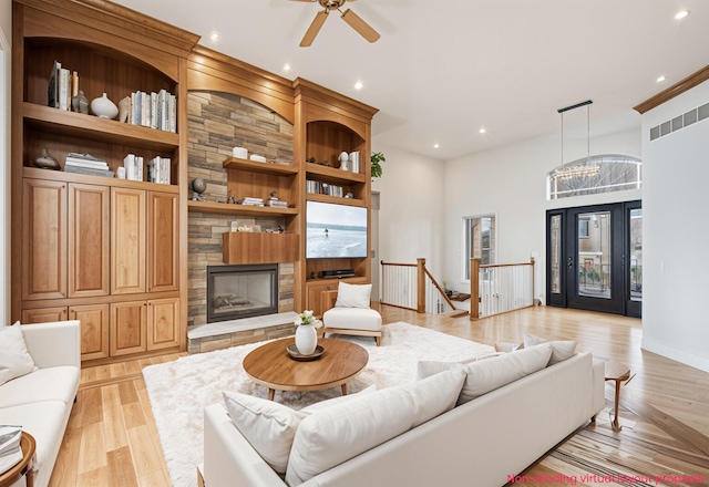 living area with built in features, recessed lighting, a large fireplace, and light wood-style floors