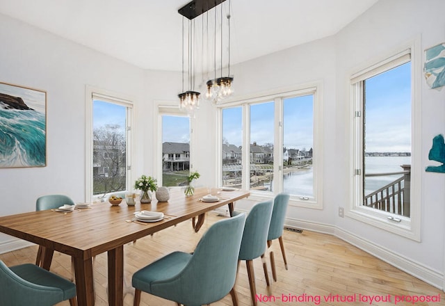 dining area with baseboards, a notable chandelier, visible vents, and light wood finished floors