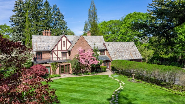 view of front of house featuring a front lawn, a high end roof, stucco siding, and a chimney