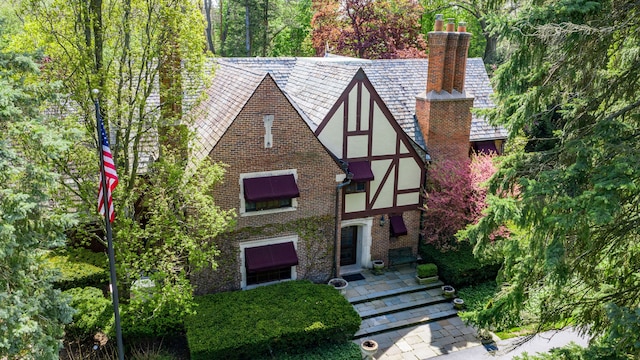 tudor-style house with brick siding, stucco siding, and a chimney