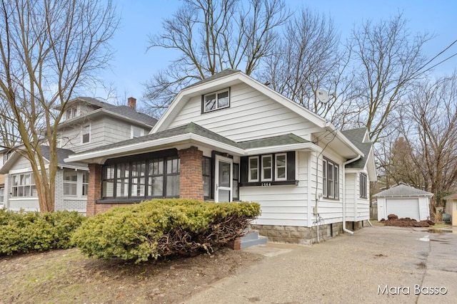 view of front of home featuring a garage, driveway, a shingled roof, a chimney, and an outdoor structure