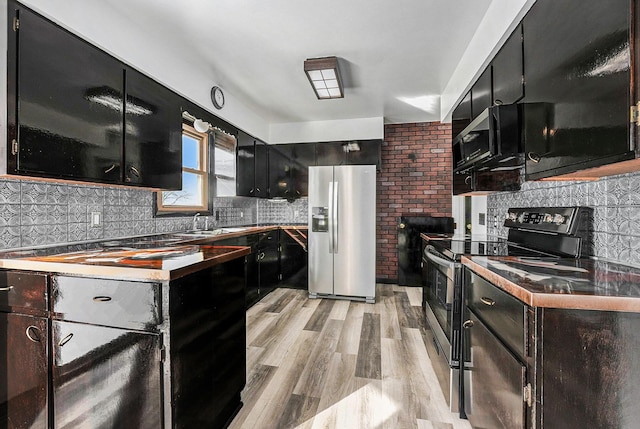 kitchen featuring decorative backsplash, light wood-style floors, appliances with stainless steel finishes, and dark cabinets