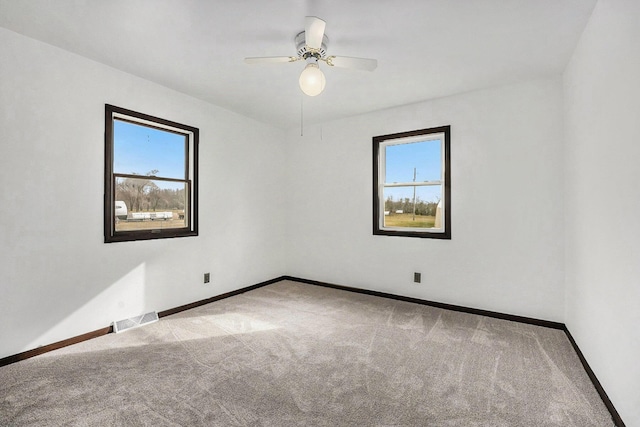 empty room with visible vents, ceiling fan, baseboards, and carpet