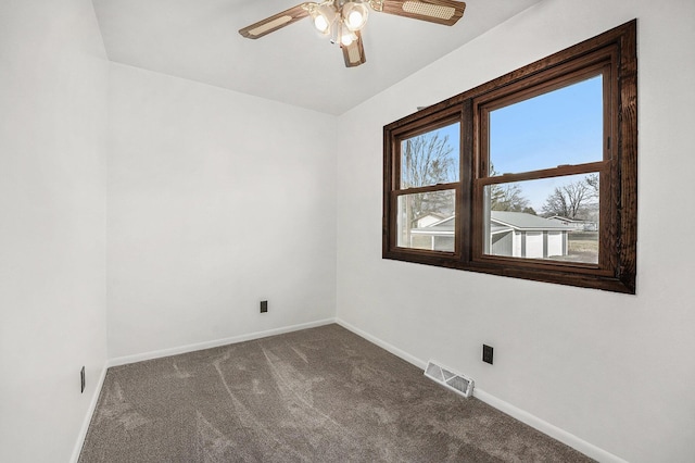 empty room featuring visible vents, baseboards, ceiling fan, and dark carpet