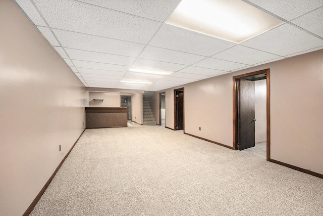 finished basement with stairway, baseboards, carpet, and a drop ceiling