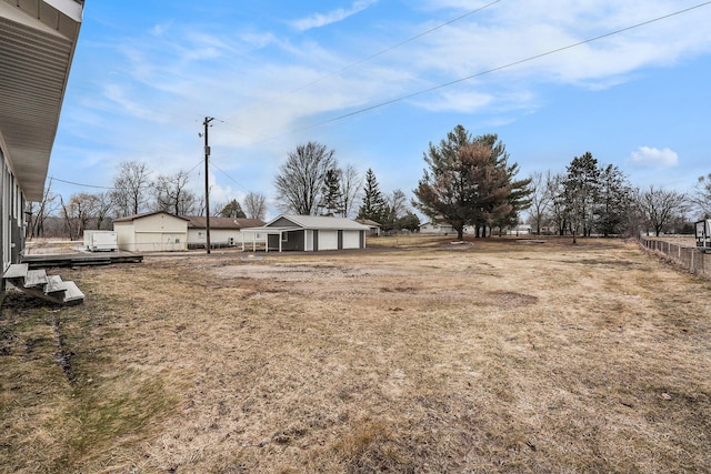 view of yard featuring a detached garage, an outdoor structure, and fence