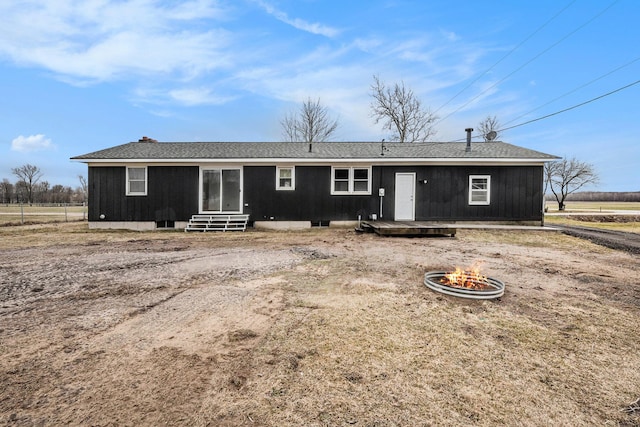 view of front of home featuring entry steps, an outdoor fire pit, and a shingled roof