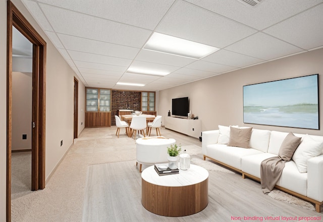 living room with a drop ceiling, baseboards, and light carpet