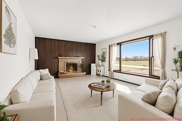 living area featuring a glass covered fireplace, wooden walls, and light carpet