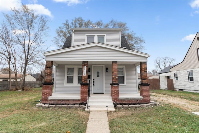 view of front of property with covered porch, fence, and a front lawn