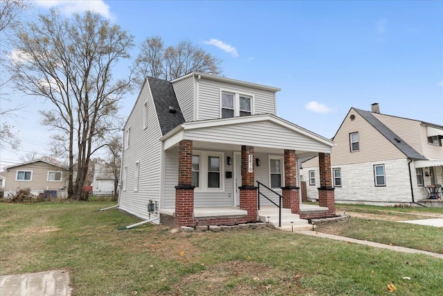 view of front of house featuring a shingled roof, a porch, and a front yard