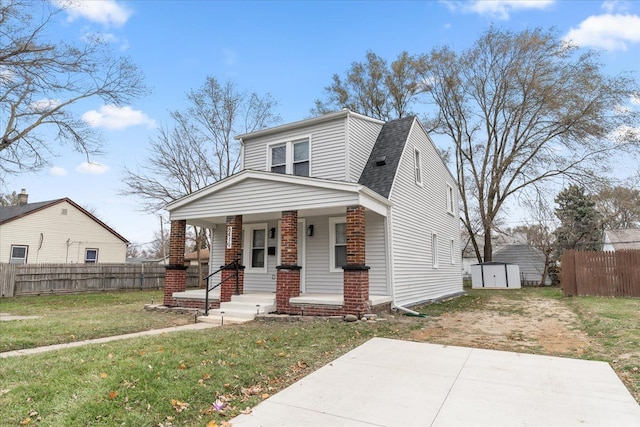 bungalow-style home with covered porch, roof with shingles, a front yard, and fence