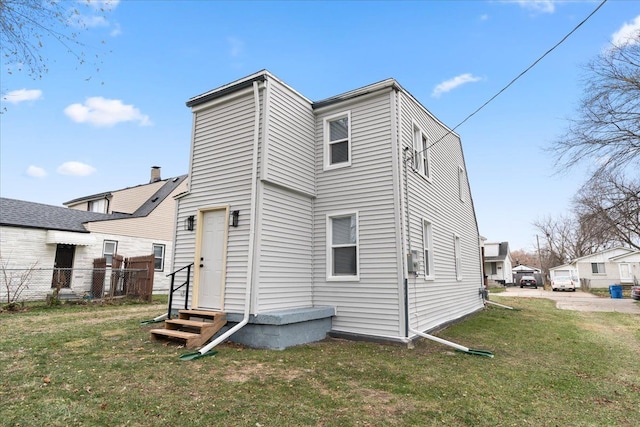 back of house featuring entry steps and a yard