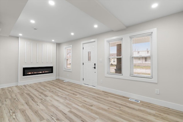 unfurnished living room featuring recessed lighting, visible vents, a wealth of natural light, and wood finished floors