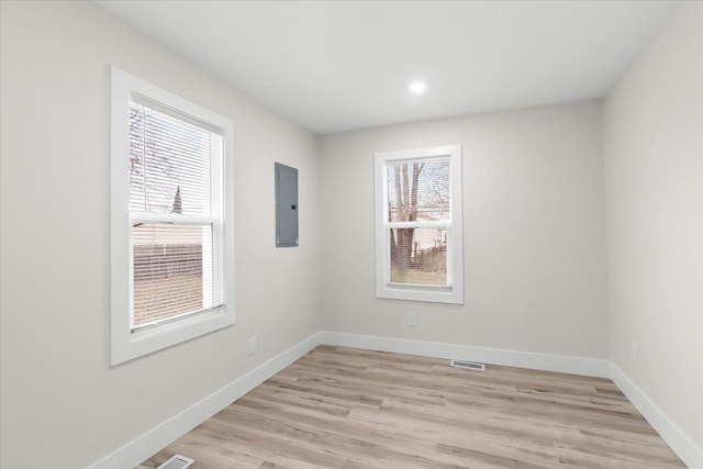 unfurnished room featuring baseboards, electric panel, and a healthy amount of sunlight