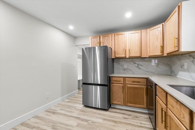 kitchen with appliances with stainless steel finishes, light countertops, light wood-style floors, and tasteful backsplash