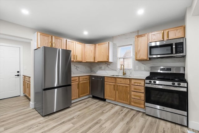 kitchen with stainless steel appliances, light wood-type flooring, a sink, and light countertops