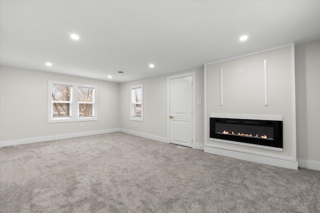 unfurnished living room with baseboards, carpet, a glass covered fireplace, and recessed lighting