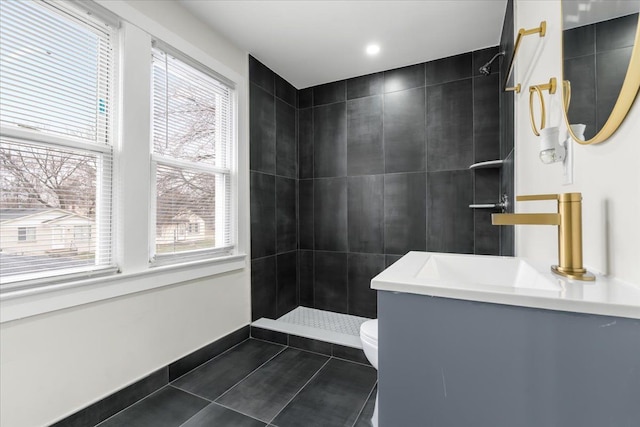 bathroom featuring baseboards, toilet, tile patterned floors, a tile shower, and vanity