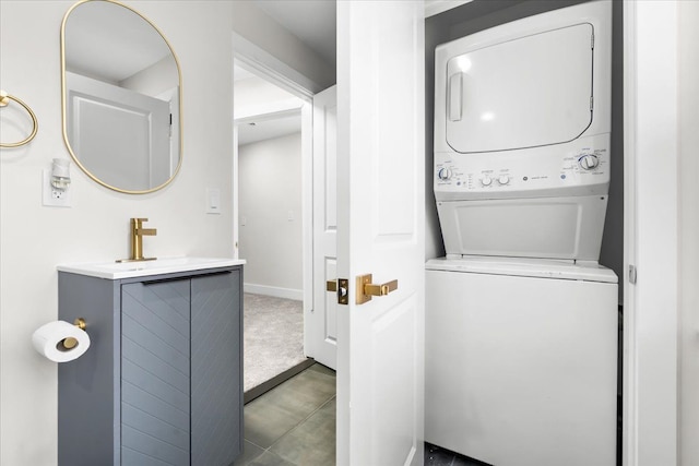 laundry room with carpet floors, stacked washer and clothes dryer, a sink, laundry area, and baseboards