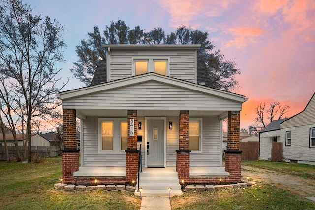 view of front of property featuring covered porch, a front yard, and fence