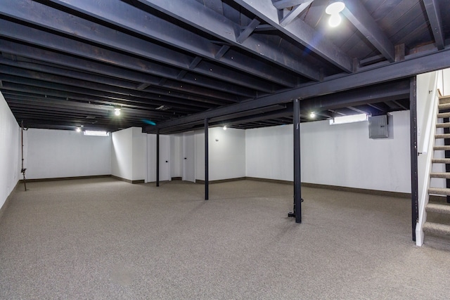 finished basement featuring electric panel, baseboards, and stairs