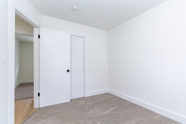 unfurnished bedroom with baseboards, a closet, and light colored carpet