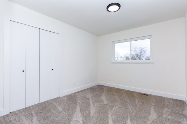 unfurnished bedroom featuring a closet, carpet, visible vents, and baseboards