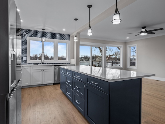 kitchen with white cabinets, stainless steel appliances, light wood-style flooring, and a center island