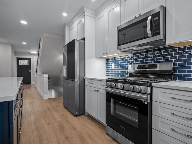 kitchen with light wood finished floors, light stone counters, stainless steel appliances, and decorative backsplash