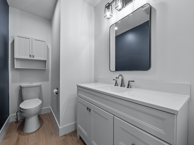 bathroom with vanity, wood finished floors, toilet, and baseboards