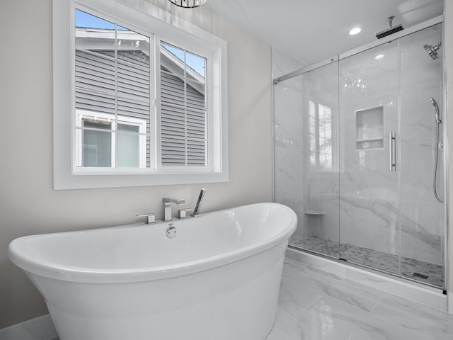 full bathroom with a freestanding tub and a marble finish shower