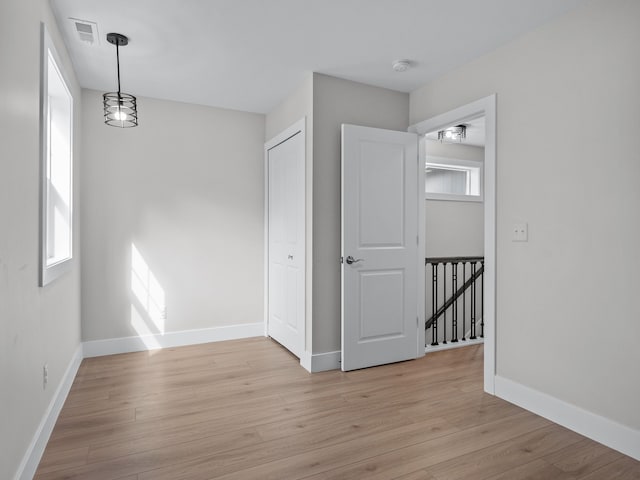 empty room featuring a wealth of natural light, light wood-style flooring, and baseboards