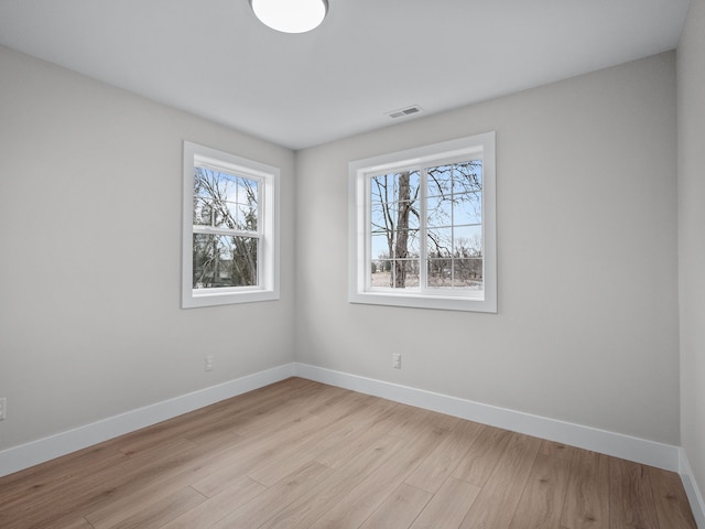 empty room featuring baseboards, visible vents, and light wood-style floors