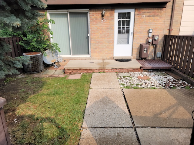 property entrance featuring fence, central AC, and brick siding