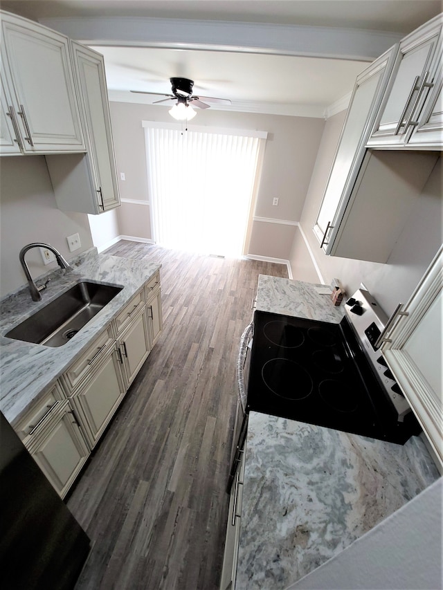 kitchen with light stone counters, a sink, stainless steel electric range, and wood finished floors