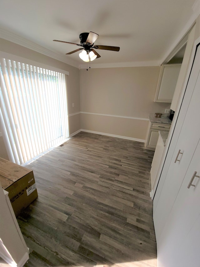 interior space with ceiling fan, ornamental molding, dark wood finished floors, and baseboards