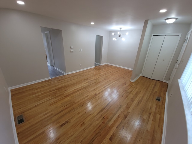 spare room featuring light wood-style floors, recessed lighting, a notable chandelier, and baseboards