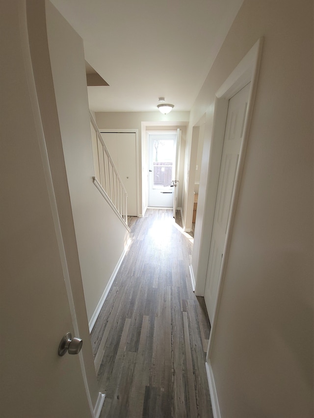 hall featuring baseboards, stairway, and wood finished floors