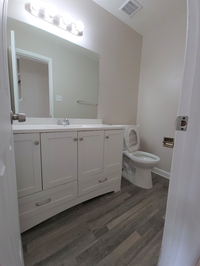 bathroom with visible vents, vanity, toilet, and wood finished floors