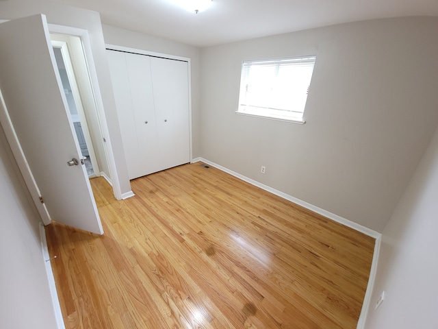 unfurnished bedroom featuring a closet, visible vents, light wood-style flooring, and baseboards