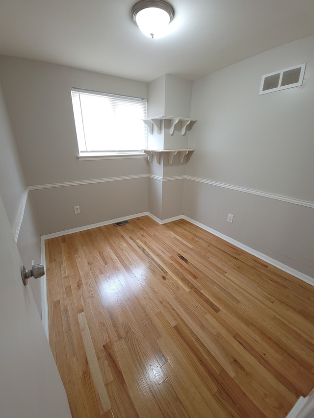 spare room with light wood finished floors, visible vents, and baseboards